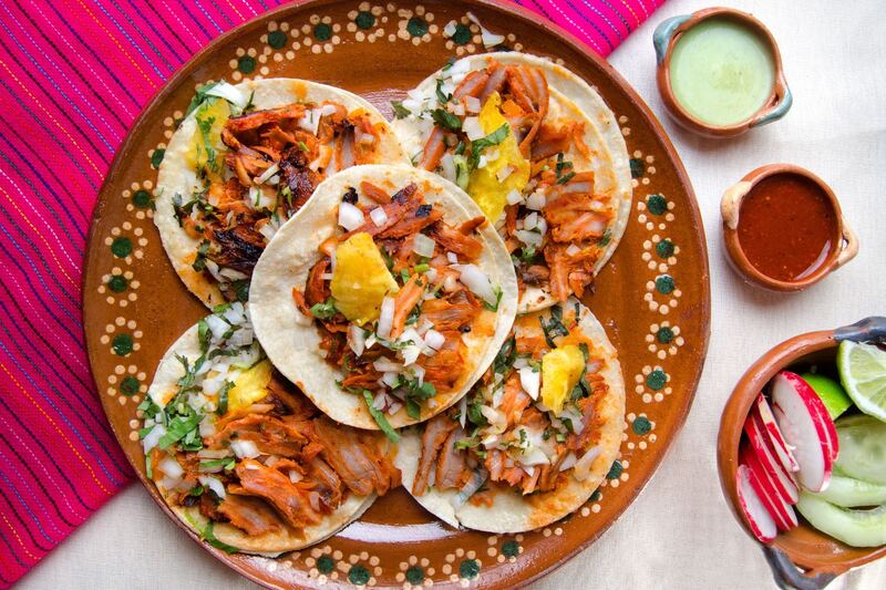 Plato de barro con cuatro tacos al pastor y salsas
